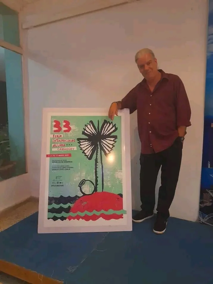 De pie junto al cartel de la 33 Feria Internacional del Libro de Camagüey