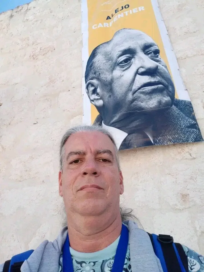 Retrato ante un gran cartel con el rostro de Alejo Carpentier