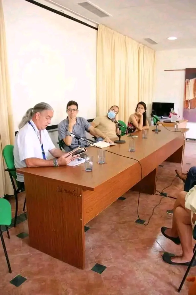 Mesa larga con varios participantes durante un panel de lecturas y debates