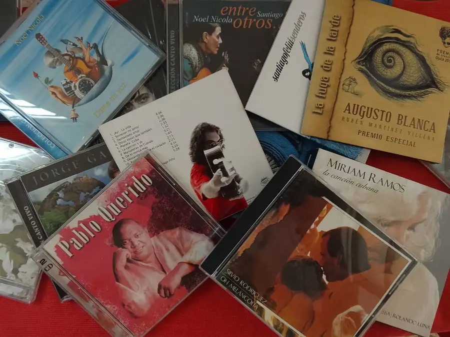 Discos de trova cubana desplegados sobre un paño rojo, entre ellos Noel Nicola, Augusto Blanca, Pablo Milanés, Silvio Rodríguez y Miriam Ramos