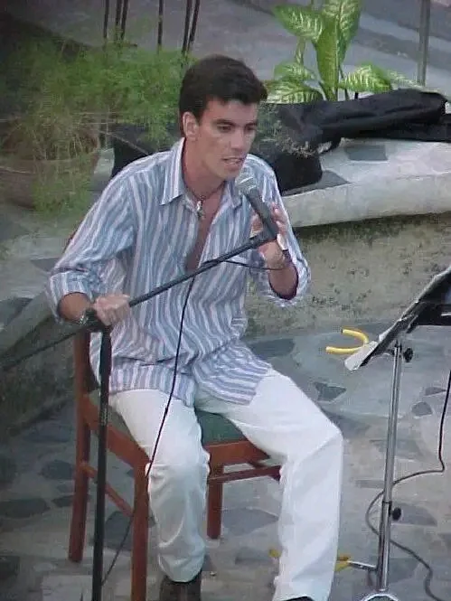 Lectura de poemas sentado ante el micrófono en el mismo concierto