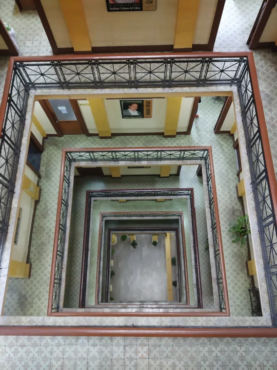 La cage d'une cour intérieure vue d'en haut, les rambardes de chaque étage emboîtées l'une dans l'autre jusqu'au fond
