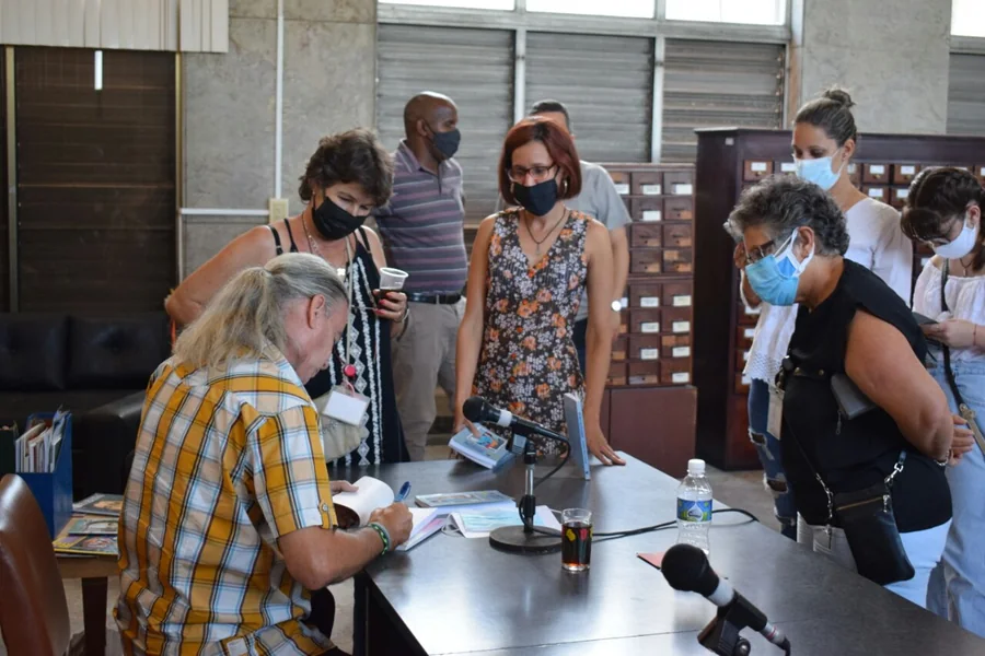Signing copies after the launch, surrounded by the audience